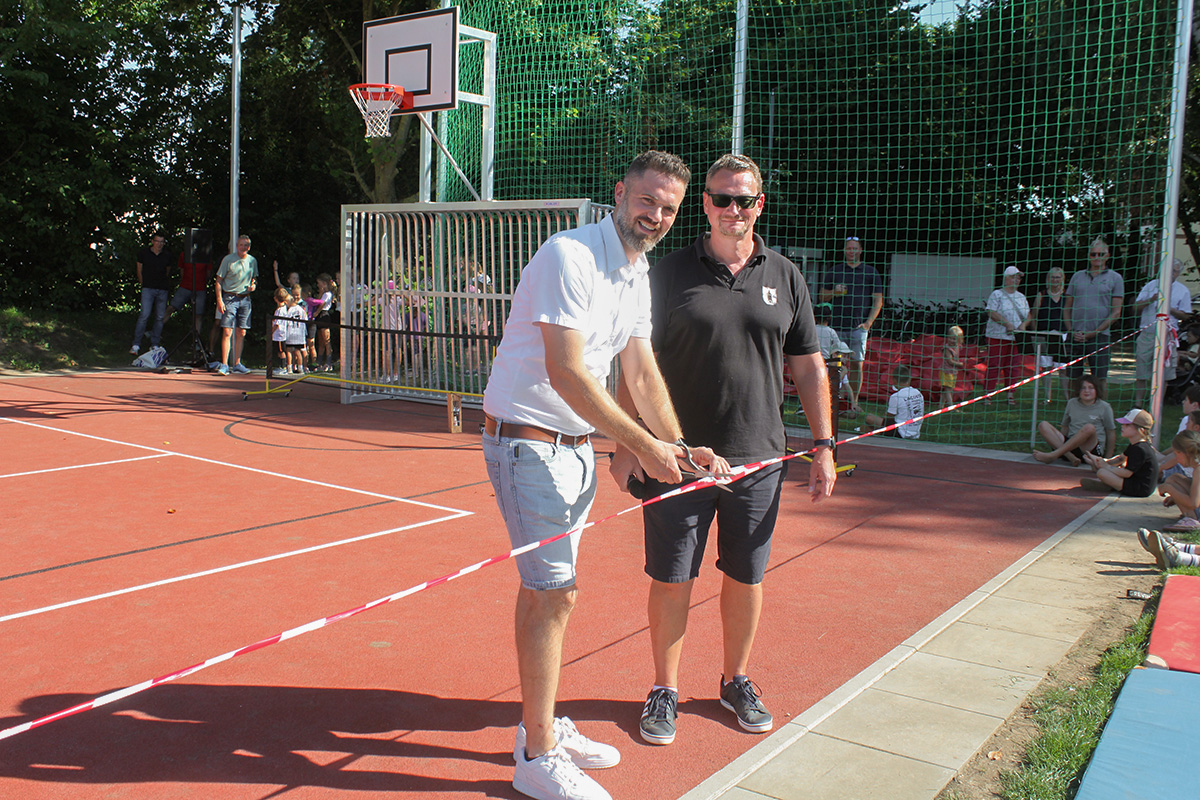 Bürgermeister Marcel Litfin und Ortsbürgermeister Frank Müller schneiden zur Eröffnung der Sportfeldes das Band durchgeführt.