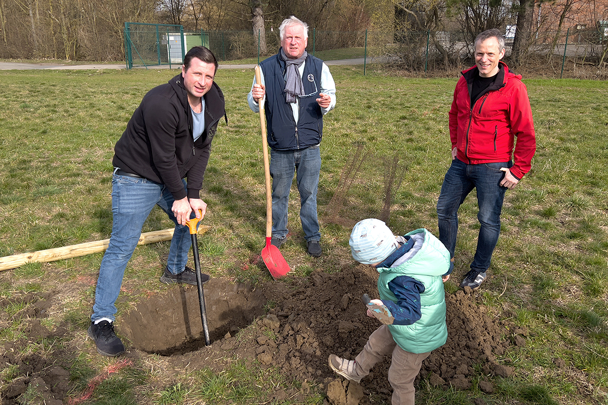 Drei Männer heben eine Pflanzgrube aus und ein Kind hilft fleißig mit.
